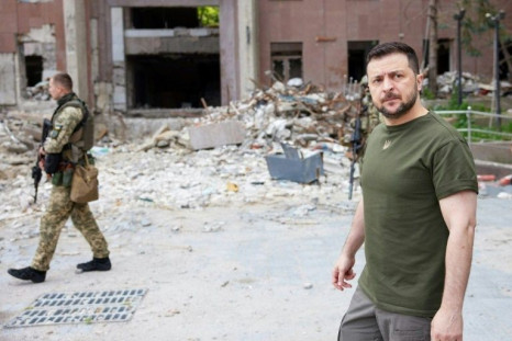 Ukrainian President Volodymyr Zelensky (R) walking past a partially destroyed building during his visit to the position of Ukrainian troops in Mykolaiv region on June 18, 2022