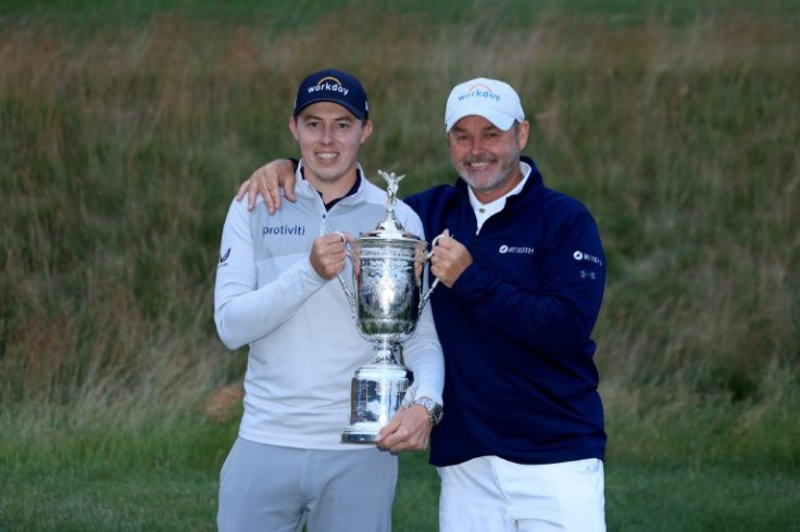 England's Matthew Fitzpatrick, left, holds the US Open champion's trophy on Sunday with his caddie Billy Foster, right, after a one-stroke victory at The Country Club
