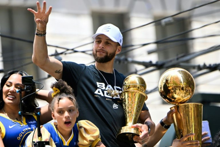 Stephen Curry (C) holds the MVP trophy as he waves from a double decker bus during the Golden State Warriors NBA Championship victory parade along Market Street in San Francisco