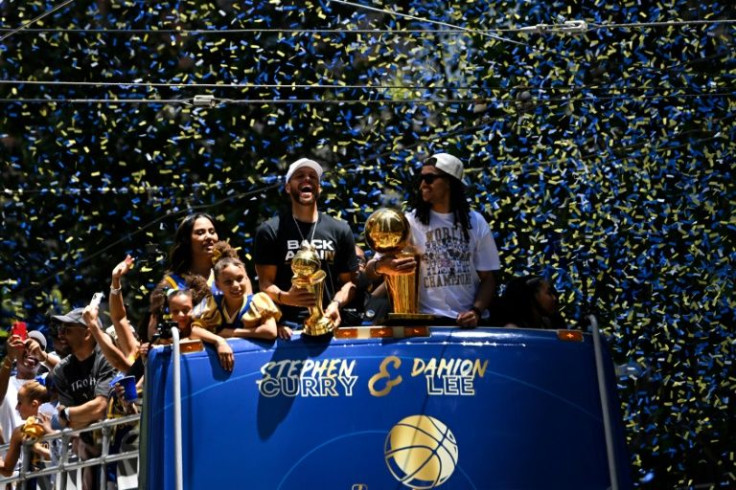 Stephen Curry (L) holds the MVP trophy alongside teammate Damion Lee (R) as they celebrate from a double decker bus during the Golden State Warriors NBA Championship victory parade along Market Street in San Francisco
