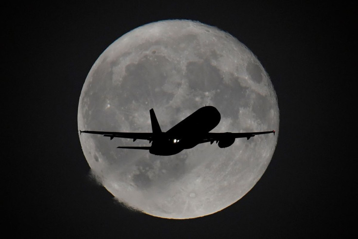 A passenger plane is seen with the moon behind as it begins its final landing approach to Heathrow Airport in London, Britain, September 25, 2018.
