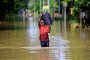 A flood-affected man carrying a luggage wades through a flooded road as he moves to a safer place after heavy rains in Nagaon district, Assam, India, June 21, 2022. 