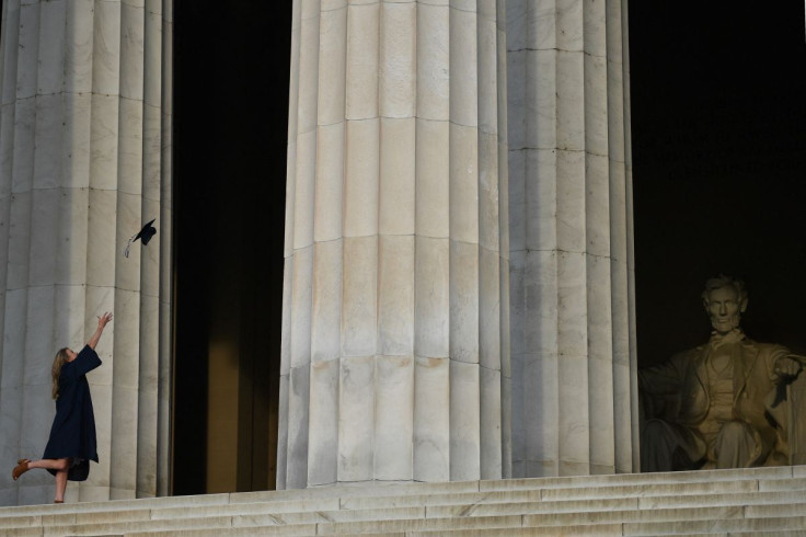 A woman throws her graduation mortar board cap in the air as she poses for her photographer in front of the Lincoln Memorial in Washington, D.C., U.S. April 30, 2019. 