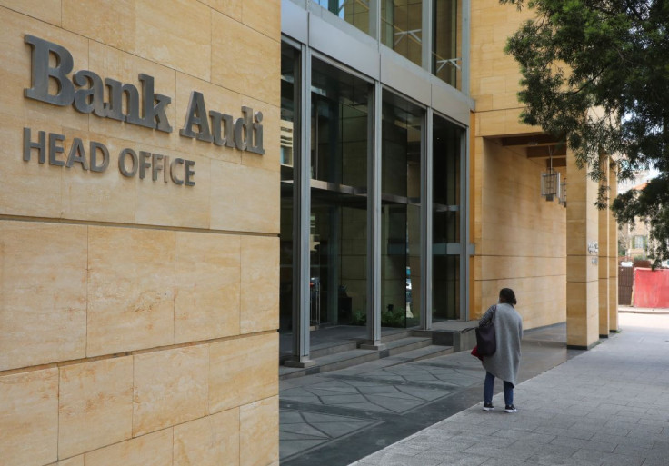 A woman stands near a logo of Bank Audi, as seen at the entrance of the Bank's head office in Beirut, Lebanon, March 4, 2022.