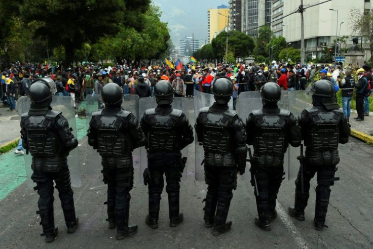 Ecuadoran police officers stand guard as Indigenous people gather in Quito