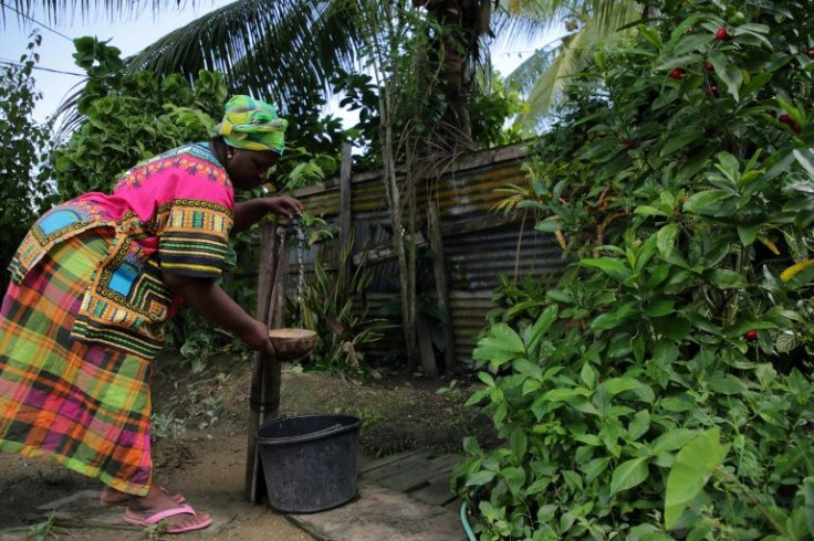 Elsy Poeketie collects water at her daughter's house in Paramaribo, Suriname, after heavy rainfall, on June 18, 2022
