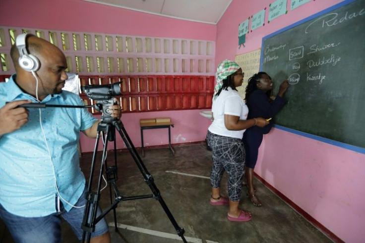 Soulamy Laurens (C) and other villagers who now live in the capital, prepare educational videos for children in flooded areas