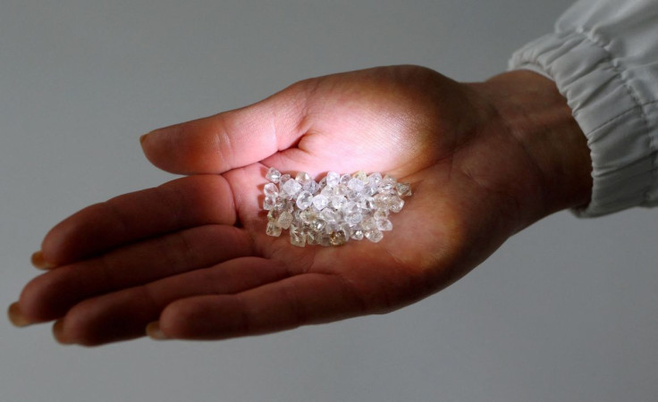 An employee shows rough diamonds at a sorting centre, owned by Alrosa company, in Moscow, October 18, 2013. 