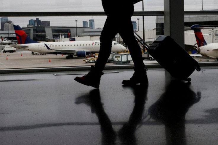 A passenger walks past a Delta Airlines plane at a gate at Logan International Airport in Boston, Massachusetts, U.S., January 3, 2022.