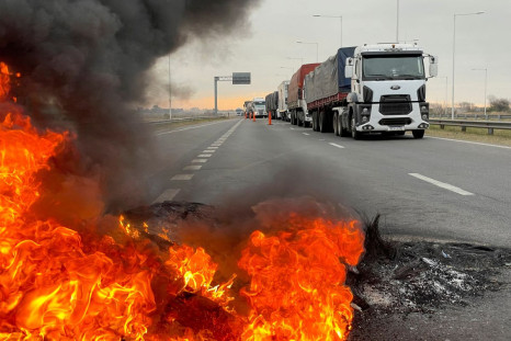 Trucks blocking a highway are pictured near a burning barricade as Argentine truck drivers protest against shortages and rising prices for diesel fuel, just as the country's crucial grains harvest requires transport amid surging inflation, in San Nicolas,