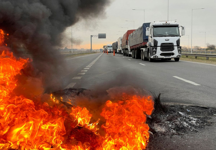 Trucks blocking a highway are pictured near a burning barricade as Argentine truck drivers protest against shortages and rising prices for diesel fuel, just as the country's crucial grains harvest requires transport amid surging inflation, in San Nicolas,