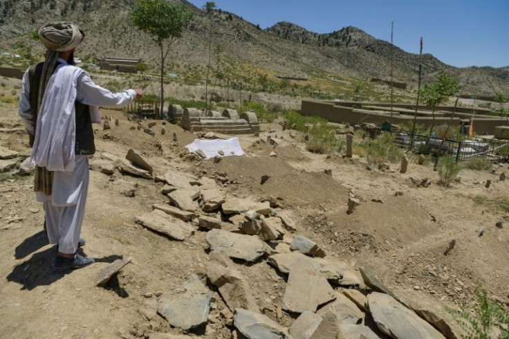 A villager looks over freshly dug graves containing victims of the deadly Afghan earthquake in Gayan district