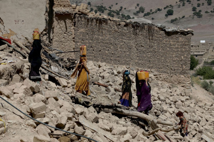 Afghan women carry water containers through the debris of damaged houses after the recent earthquake in Wor Kali village in the Barmal district of Paktika province, Afghanistan, June 25, 2022. 