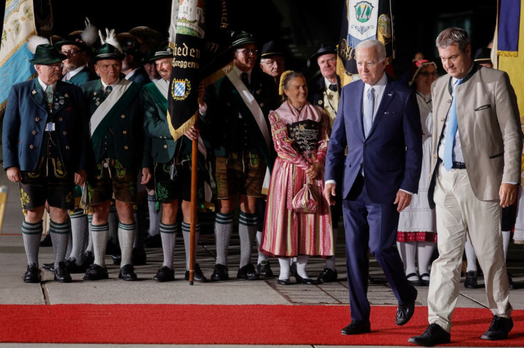 U.S. President Joe Biden walks with Bavaria's State Premier Markus Soeder past people in traditional Bavarian clothes as Biden arrives for a G7 summit aboard Air Force One at Munich International Airport near Munich, Germany June 25, 2022. 