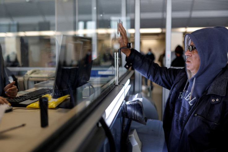 A Palestinian worker holds up his ID card as he is processed after entering Israel through the Erez Crossing, on the border with Gaza, February 20, 2022. 