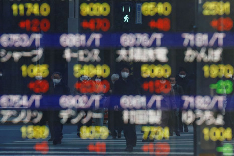 Pedestrians wearing protective masks are reflected on an electronic board displaying various companyâs stock prices outside a brokerage in Tokyo, Japan, February 25, 2022. 