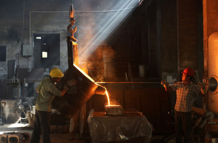 Workers pour molten iron into a mould at a workshop in Hangzhou, Jiangsu province, China July 24, 2019. 
