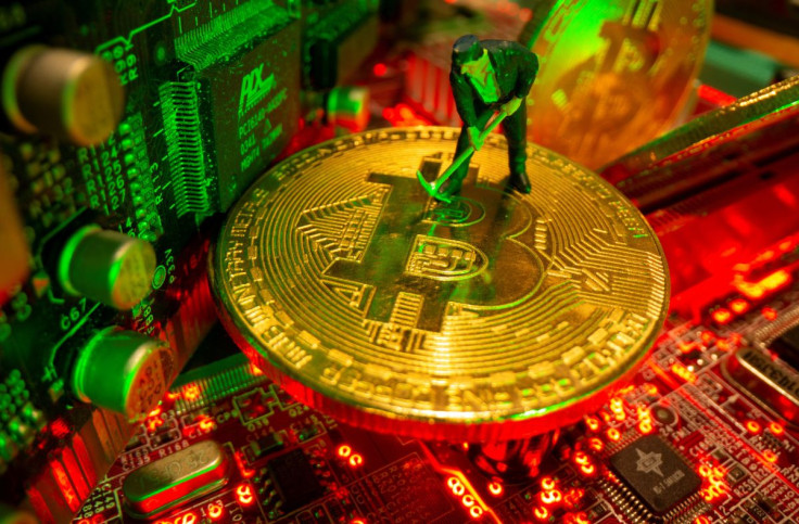 A small toy figure and representations of the virtual currency bitcoin stand on a motherboard in this picture illustration taken May 20, 2021. 