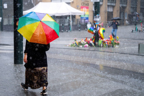 A woman walks with a rainbow-themed umbrella near the site of the recent deadly mass shooting at a gay bar in Oslo, Norway June 27, 2022. NTB/Beate Oma Dahle via REUTERS