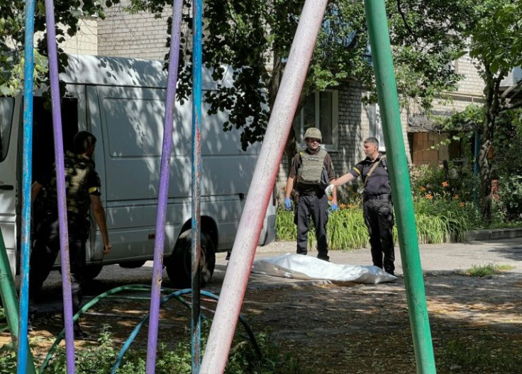 Policemen stand next to the covered body of a man killed in a Russian strike on a residential area of Sloviansk