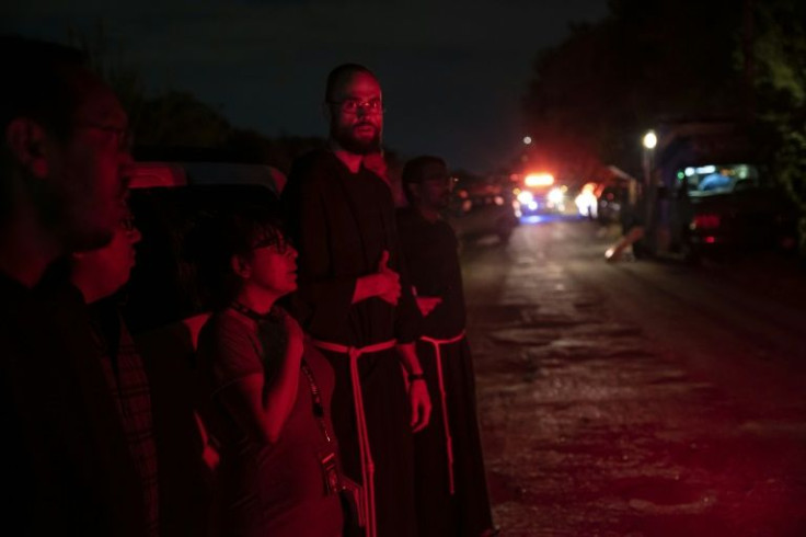 Local priests from the San Antonio Archdiocese stand near where dozens of dead migrants were found inside a tractor-trailer in San Antonio, Texas on June 27, 2022