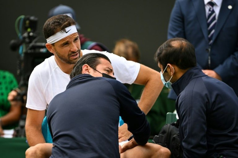 Bulgaria's Grigor Dimitrov receives help from masked medical staff at Wimbledon