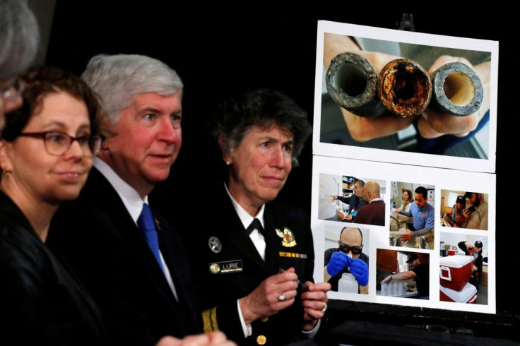 A pictures of damaged pipes from Flint, a city struggling with the effects of lead-poisoned drinking water, is seen as Michigan Governor Rick Snyder (2nd L) attends a meeting between local and federal authorities with U.S. President Barack Obama in Michig