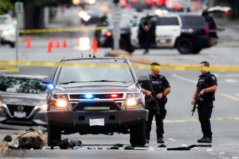 Police officers gather after two armed men entering a bank were killed in a shootout with police in Saanich, British Columbia, Canada June 28, 2022. 