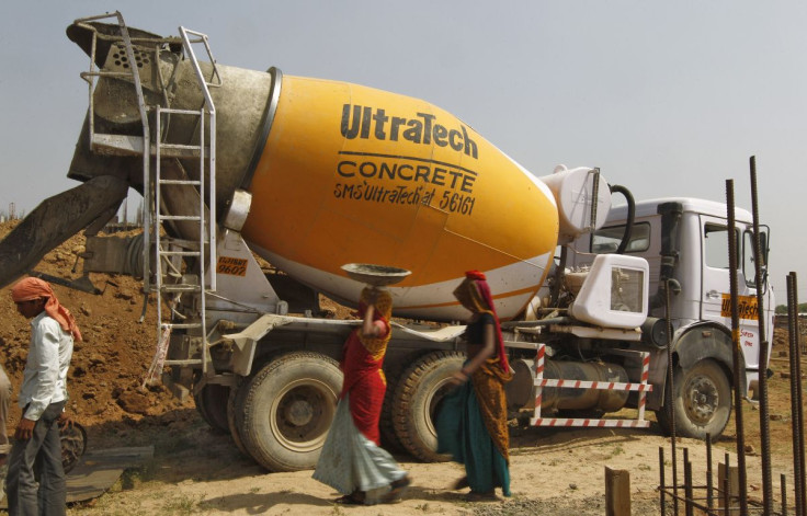 Workers walk in front of an UltraTech concrete mixture truck at the construction site of a commercial complex on the outskirts of the western Indian city of Ahmedabad April 22, 2013.  