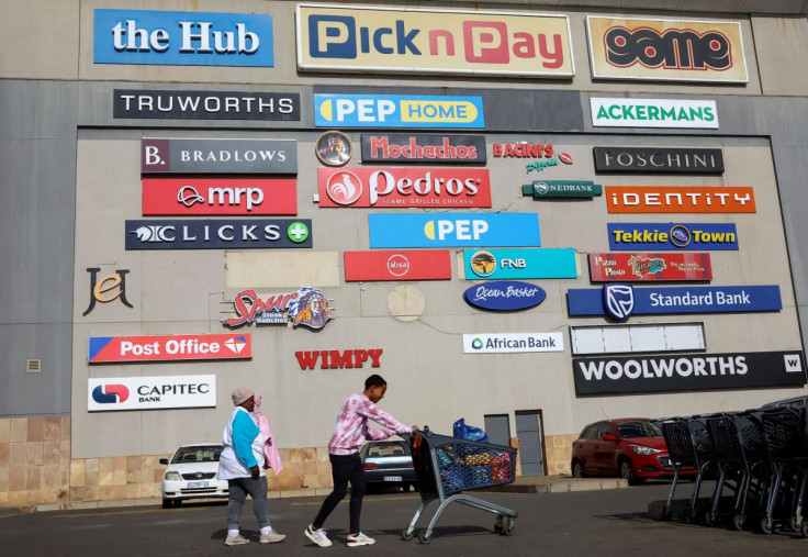 A shopper pushes a trolley as logos of shops are seen on a wall at a shopping mall in Lenasia, south of Johannesburg, South Africa, June 28, 2022. 