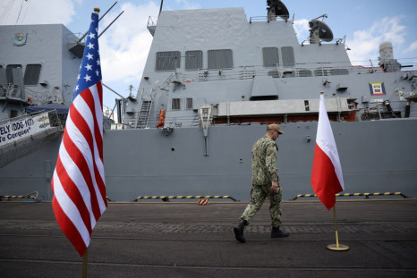 A U.S. Marine walks between U.S. and Polish flag before conference in front of U.S. Navy's warship USS Gravely which docked in the Baltic sea port city of Gdynia in what was described by officials as a show of support for the country as war rages in neigh