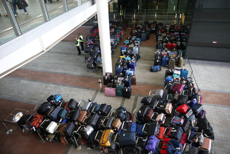 Airport workers stand next to lines of passenger luggage arranged outside Terminal 2 at Heathrow Airport in London, Britain, June 19, 2022.