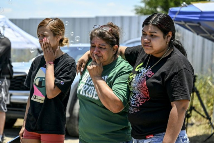 Maria Lopez (C) cries as she visits a makeshift memorial to the 53 people migrants who died near San Antonio after being abandoned by traffickers in an overheated tractor-trailer.