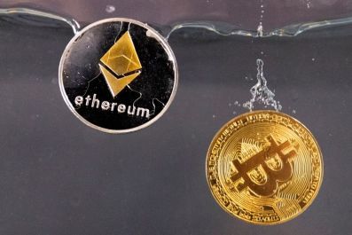 Souvenir tokens representing cryptocurrency Bitcoin and the Ethereum network, with its native token ether, plunge into water in this illustration taken May 17, 2022. 
