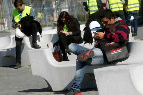 People use their mobile phones near the entrance to Mobile World Congress in Barcelona February 22, 2014. 