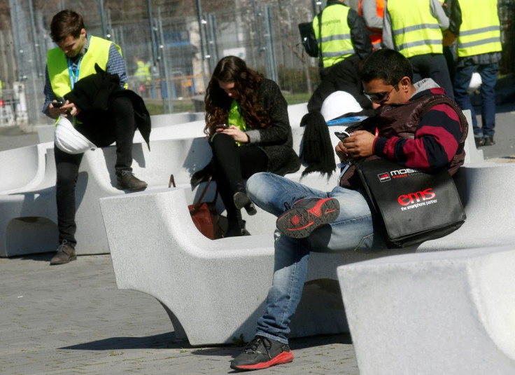 People use their mobile phones near the entrance to Mobile World Congress in Barcelona February 22, 2014. 