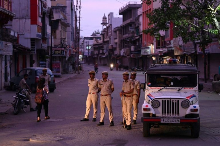 Police stand guard along a deserted street in Udaipur during a curfew imposed by authorities following the killing of Hindu tailor Kanhaiya Lal, allegedly by two Muslim men