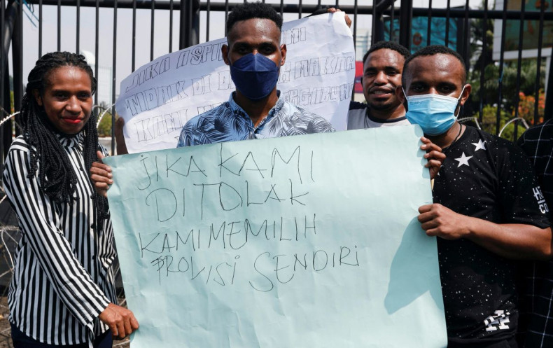 Demonstrators hold a sign as they protest outside the Indonesian Parliament following a bill passed by legislators to create three new provinces in its underdeveloped region of Papua, in Jakarta, Indonesia, June 30, 2022. 