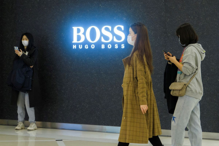 People walk past a store of German fashion house Hugo Boss in Beijing, China, March 27, 2021.
