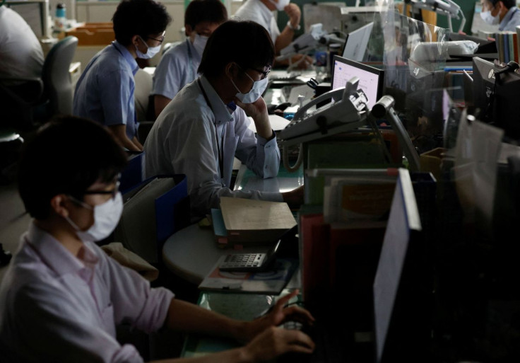 Employees of Tokyo Metropolitan Government office work inside the office with partially switched off lights during daytime to take power-saving measures as Japanese government issues warning over possible power crunch due to heatwave in Tokyo, Japan June