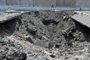 A man walks past a crater after a Russian rocket struck an industrial zone of Kharkiv on June 30, 2022