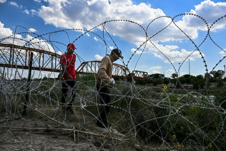 Migrants walk past concertina wire after successfully crossing into Texas