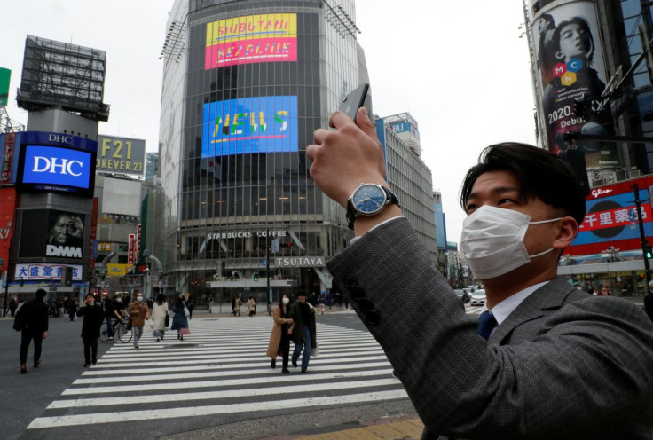 A man wearing a protective face mask, takes a photo with his mobile phone at noon, at Shibuya Crossing, during the coronavirus disease (COVID-19) outbreak, in Tokyo, Japan, March 31, 2020.