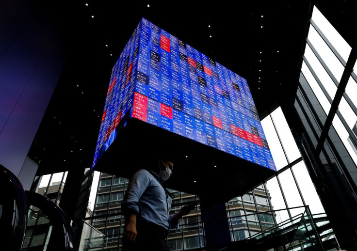 A man walks under an electronic screen showing Japan's Nikkei share price index inside a conference hall in Tokyo, Japan June 14, 2022. 