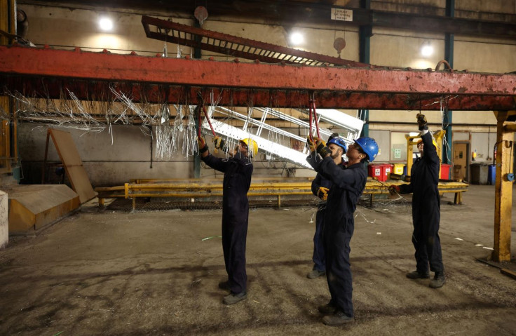 Workers remove pieces of wire from a frame inside the factory of Corbetts The Galvanizers in Telford, Britain, June 28, 2022. 