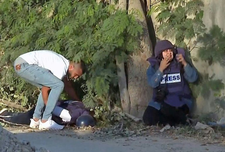 An image from footage distributed by Al Jazeera television shows a man trying to lift the body of the channel's veteran journalist Shireen Abu Akleh after she was fatally wounded by gunfire in Jenin in the occupied West Bank on May 11, 2022