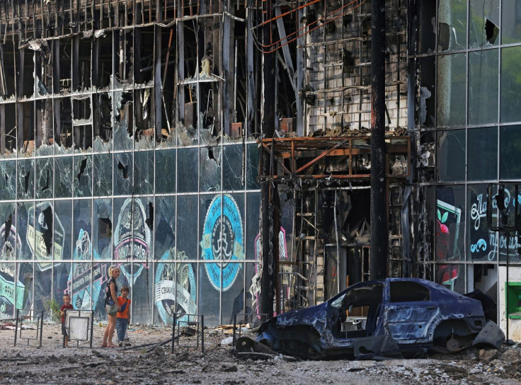 Local residents stand next to a building destroyed during Ukraine-Russia conflict in the city of Lysychansk in the Luhansk Region, Ukraine July 4, 2022. 