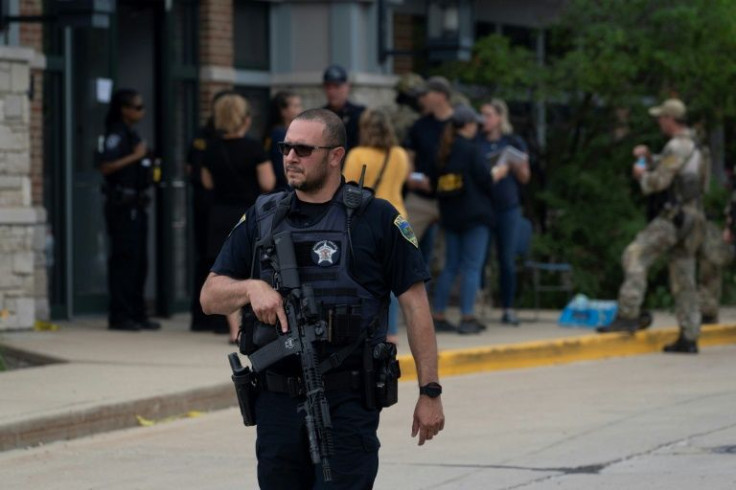 A police officer searches the scene of the Fourth of July parade shooting in Highland Park, Illinois on July 4, 2022