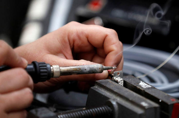 A worker solders electrical wire to a component on the factory floor of PP Control and Automation near Cannock, Britain, July 6, 2016.