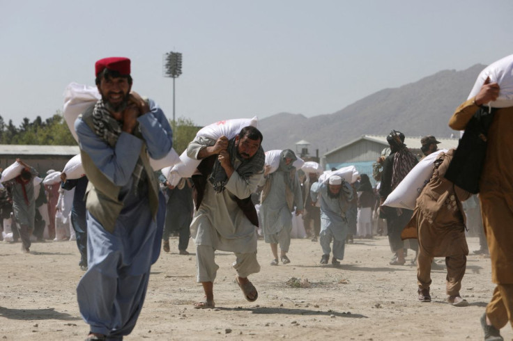 Afghan people carry sacks of rice, given out as part of humanitarian aid sent by China to Afghanistan, at a distribution centre in Kabul, Afghanistan, April 7, 2022. 